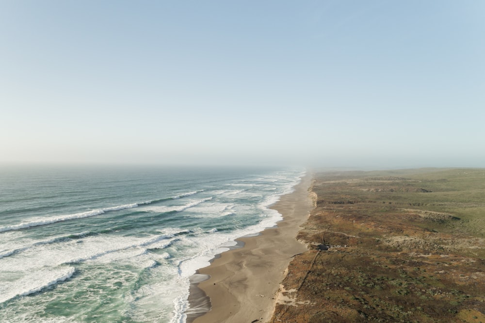 ocean near desert under white clouds during daytime