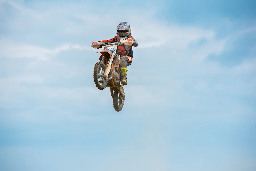 A young motocross rider in full gear catching air