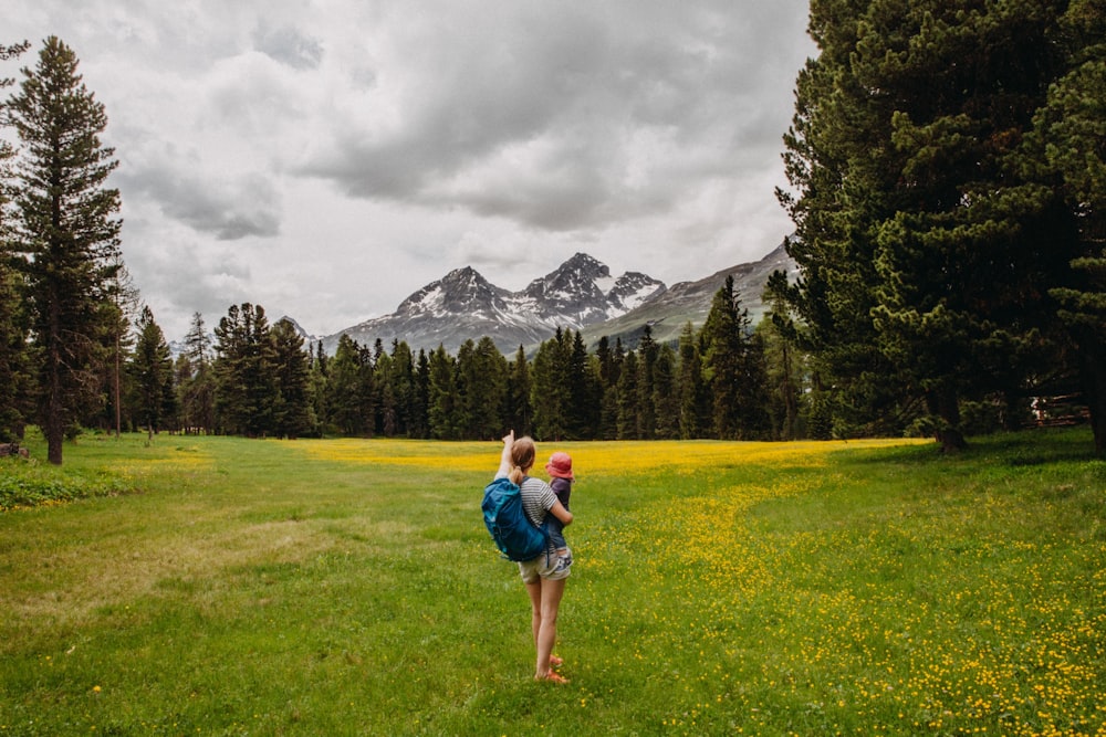 woman carrying toddler white pointing at snow-capped mountain under gloomy sky