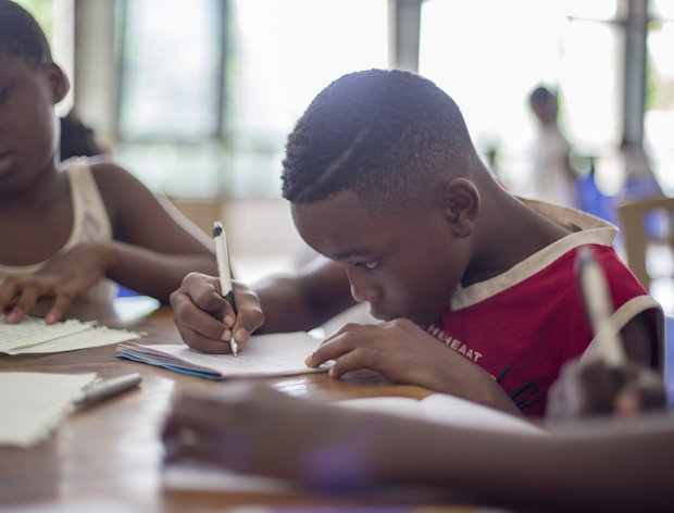 boy writing on printer paper near girl