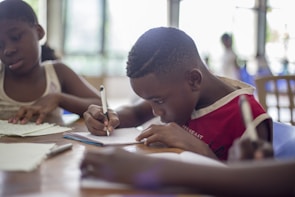A group of children gathered around a table, sharing ideas and writing.