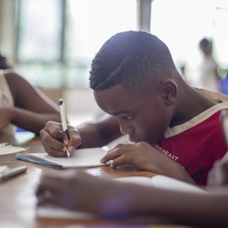 boy writing on printer paper near girl