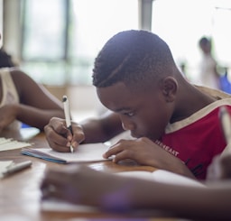 boy writing on printer paper near girl