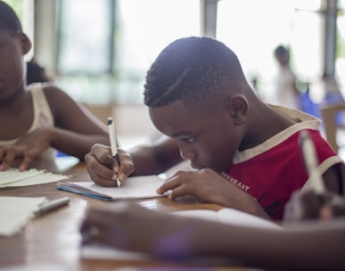 boy writing on printer paper near girl