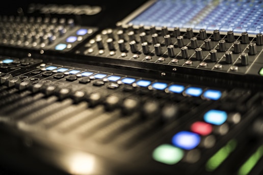 Close-up image of an analog mixing console with knobs and sliders.