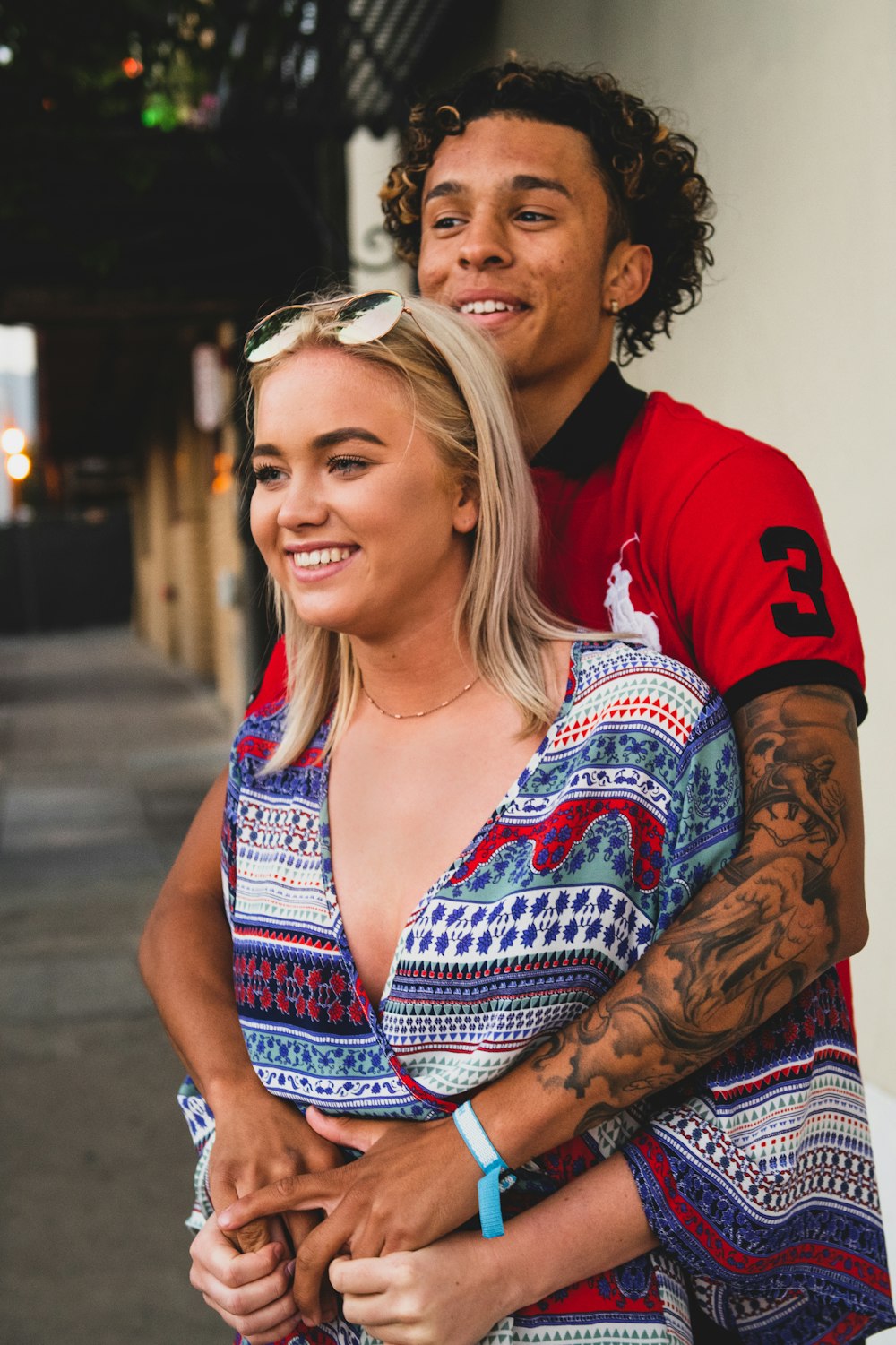 man in red t-shirt hugging woman