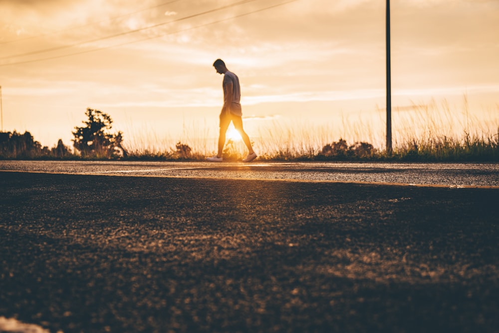 Fotografia da Hora de Ouro do Homem Caminhando na Estrada do Asfalto