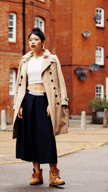 An urban setting with a woman confidently posing in a tailored trench coat and muted tones.