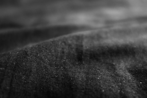 Close-up of fabric textures and details under subtle lighting, highlighting the tactile quality of the clothing.
