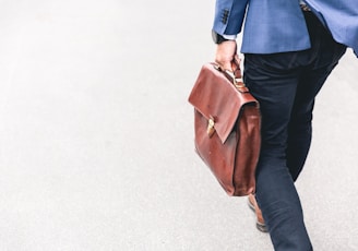 person walking holding brown leather bag