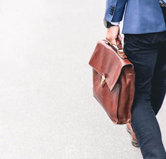 person walking holding brown leather bag