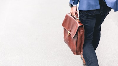 person walking holding brown leather bag