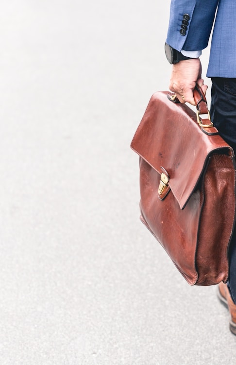 person walking holding brown leather bag