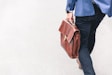 person walking holding brown leather bag