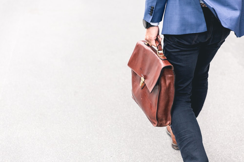 person walking holding brown leather bag