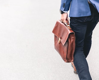 person walking holding brown leather bag