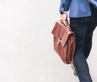 person walking holding brown leather bag