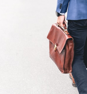 person walking holding brown leather bag