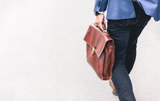 person walking holding brown leather bag