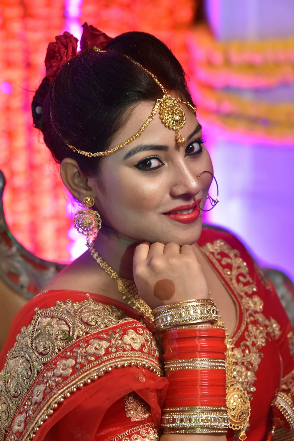 smiling woman wearing gold and red floral sari dress