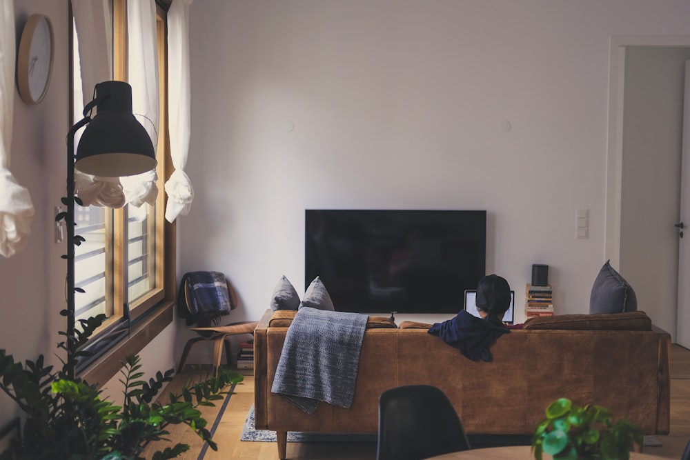 femme assise sur le canapé devant la télévision LED