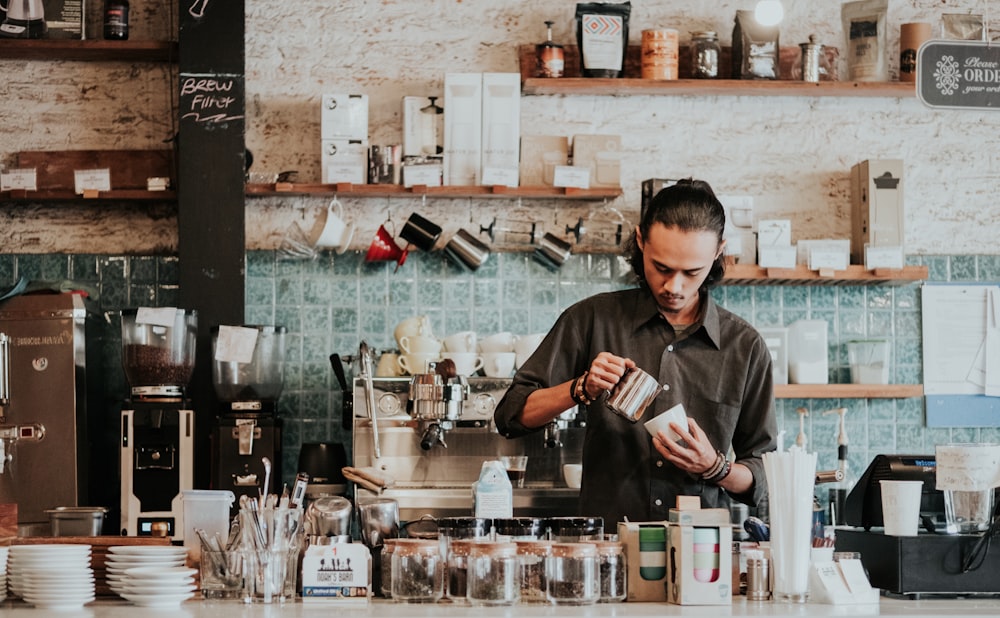 man holding cup and pitcher standing on kitchen