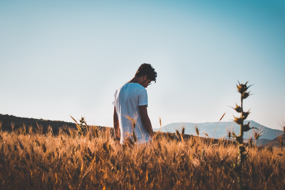 man in white top standing on brown grass