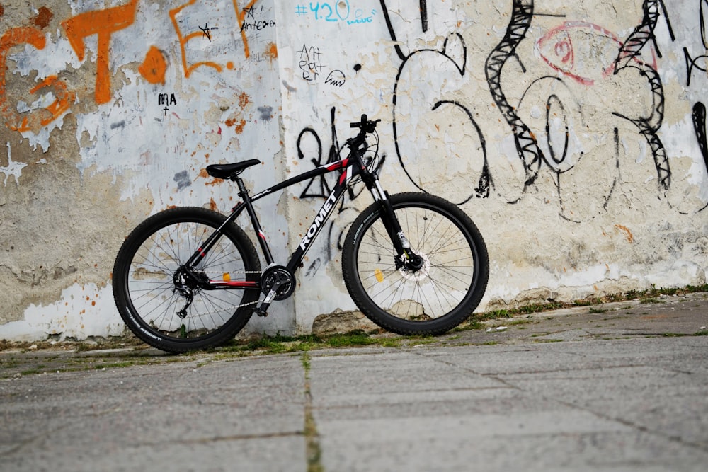 흰색 콘크리트 벽에 기대어 있는 검은색 하드테일 자전거