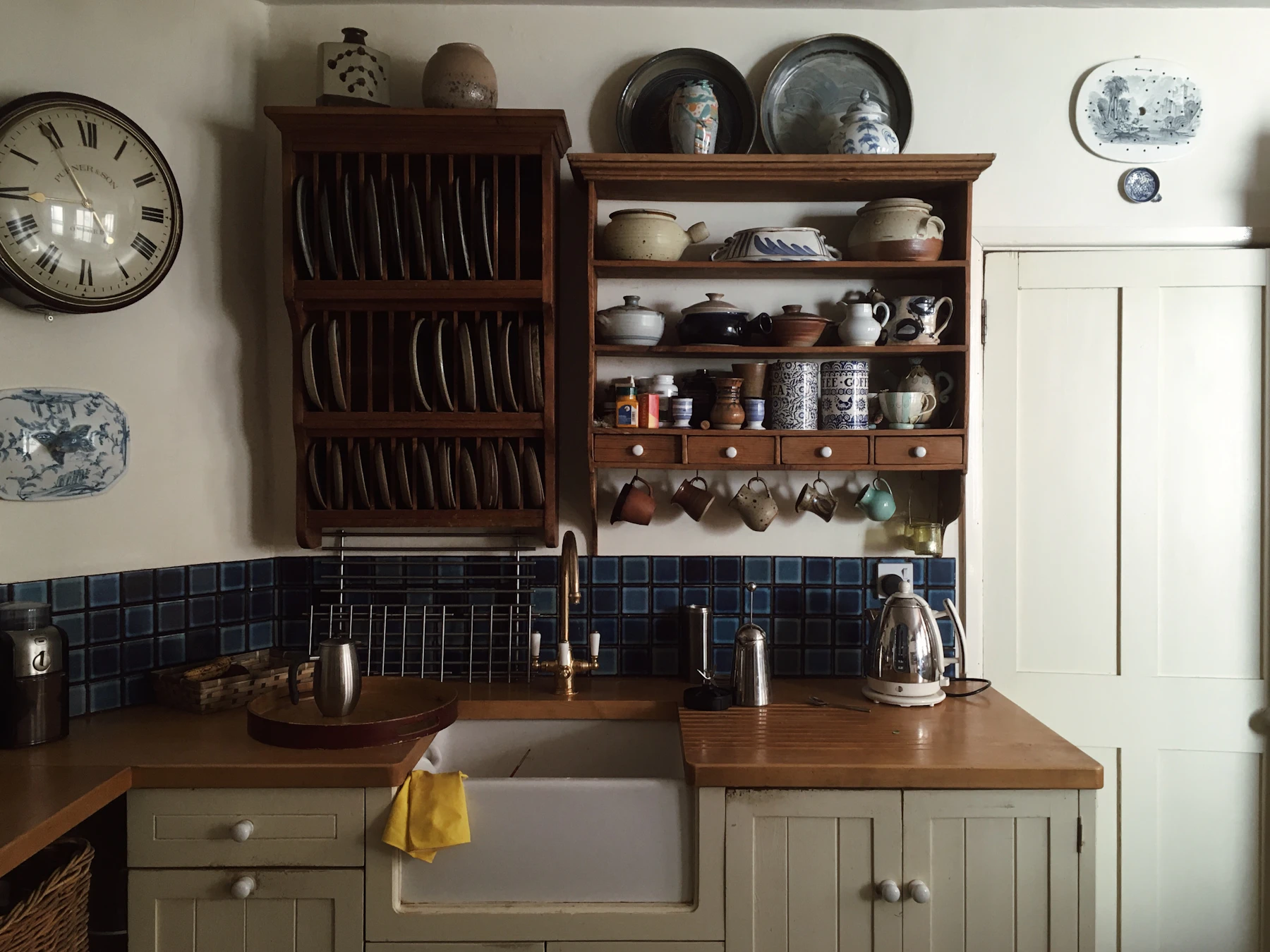 Shelves of hand-thrown stoneware dinnerware arranged in a bright kitchen