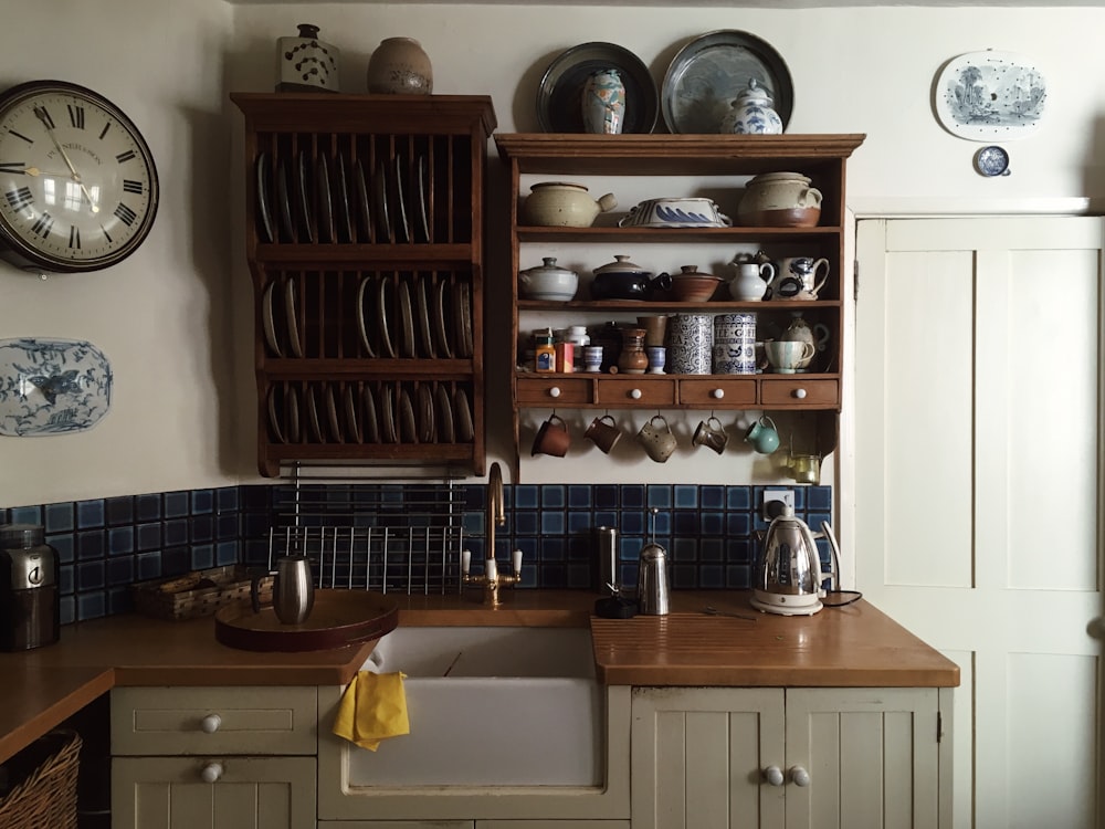 weiße Küchenschränke und Regal mit darauf angeordnetem Geschirr