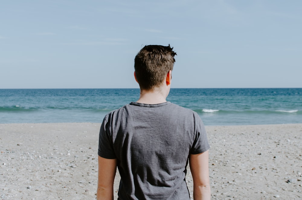 hombre de pie en la orilla de la playa durante el día