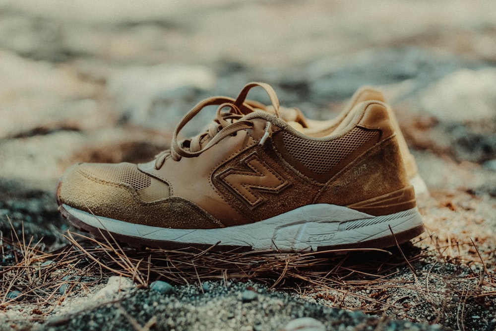 unpaired brown and white New Balance athletic shoe on ground