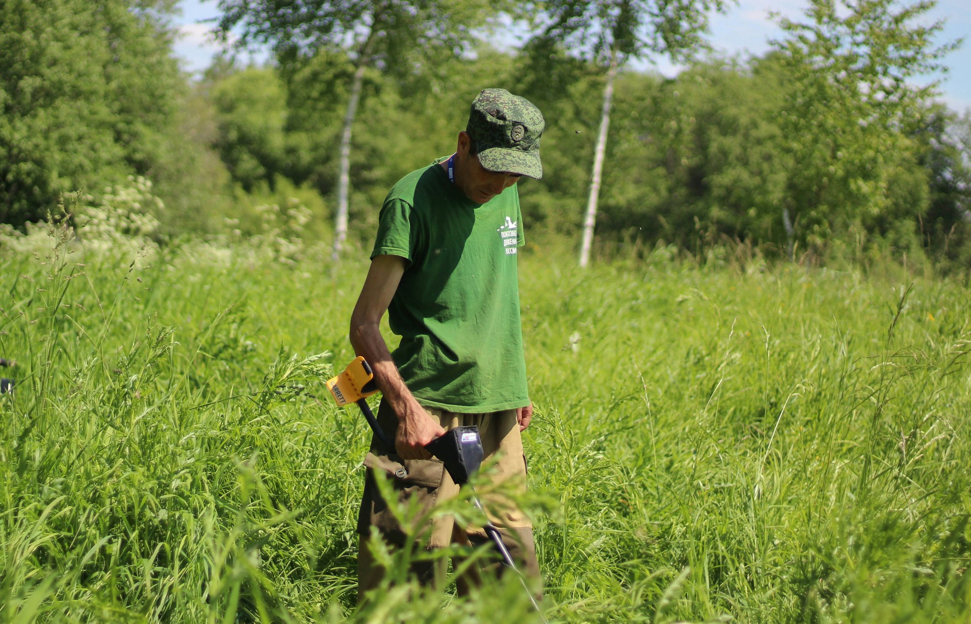 A researcher in the field using a GPS device amidst a patch of mixed agricultural and forest land, illustrating applied conservation work.