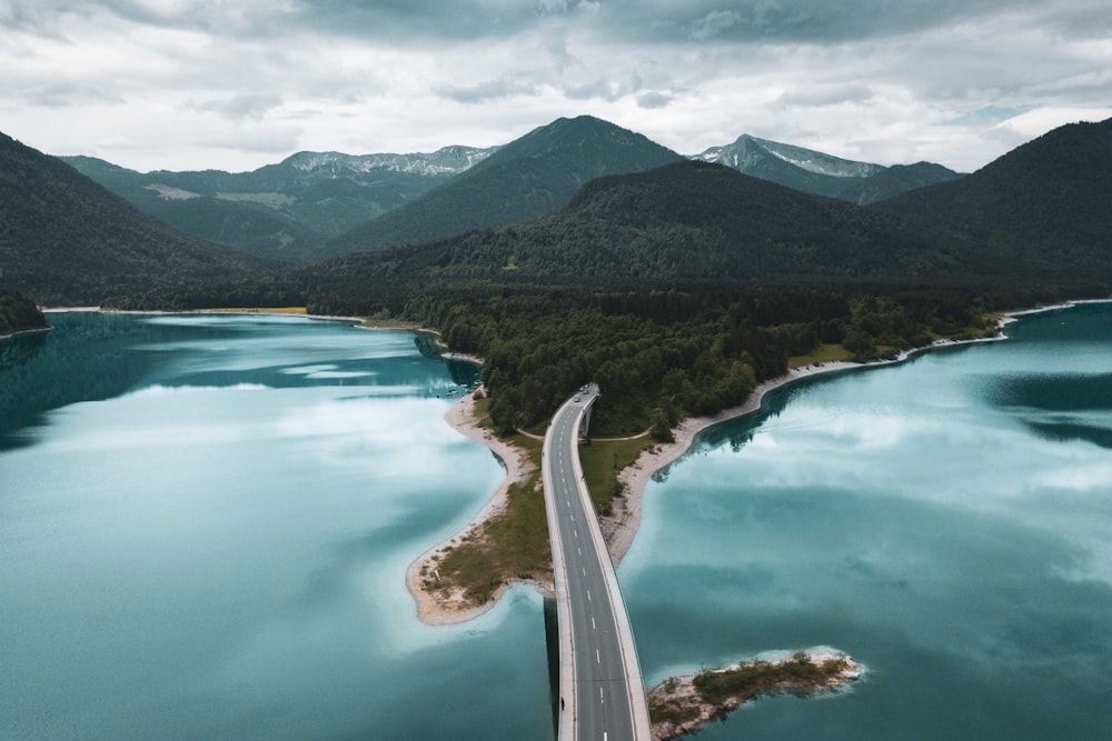 Carretera de asfalto gris con cuerpo de agua bajo el cielo azul durante el día