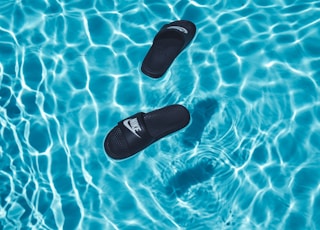 black Nike slide sandals on swimming pool