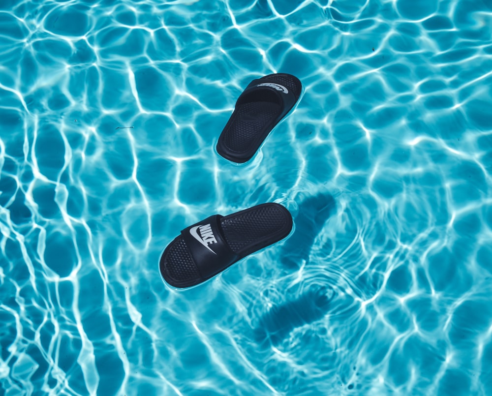 black Nike slide sandals on swimming pool