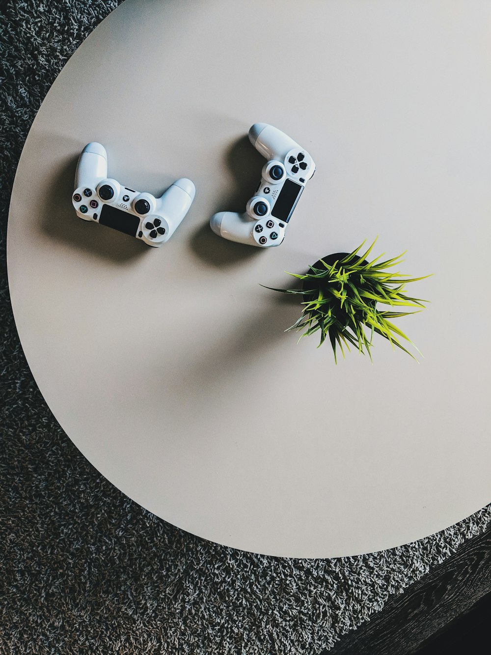 two Sony PS4 controllers on table