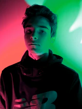 Close-up of a black hoodie with glowing red neon edges under cinematic lighting.