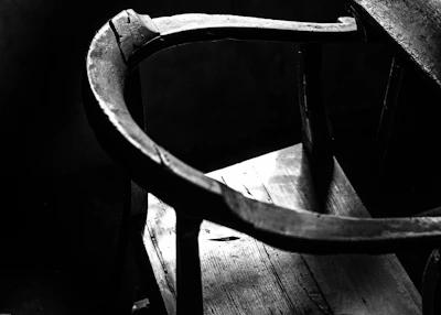 A rustic wooden chair showcasing the natural wear of years, softly lit in a minimalist setting