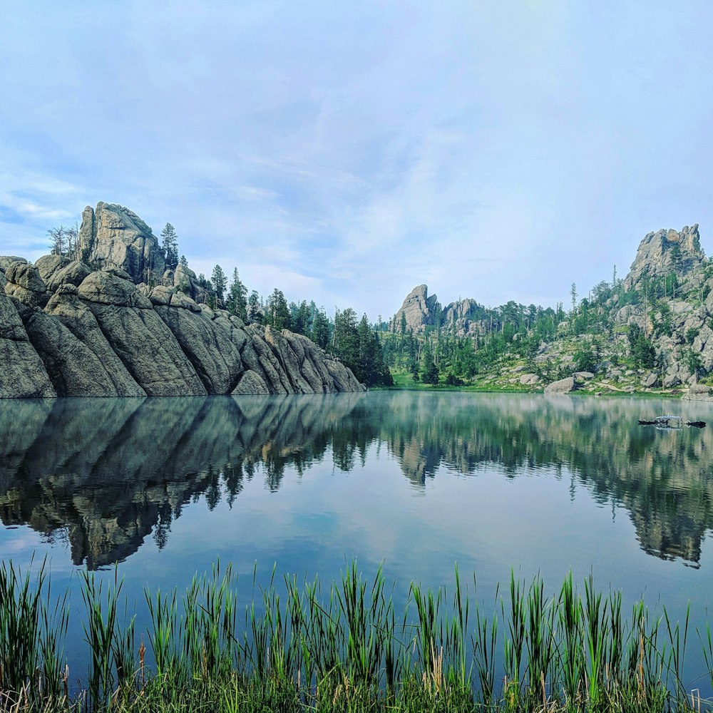 photographie de paysage d’un plan d’eau calme entouré de montagnes rocheuses