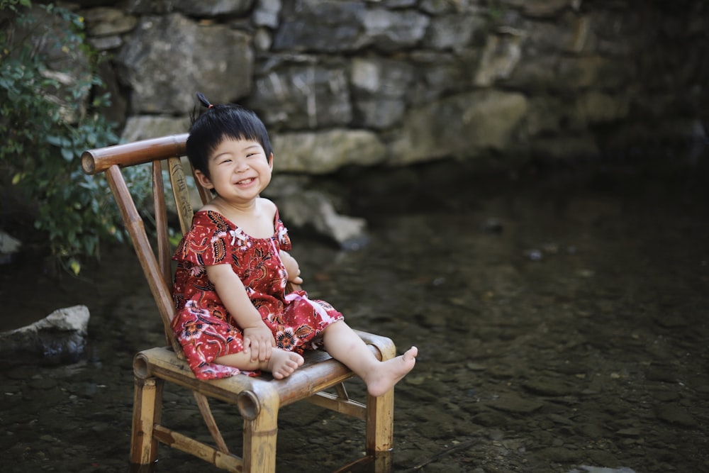 toddler sitting on brown wooden chair