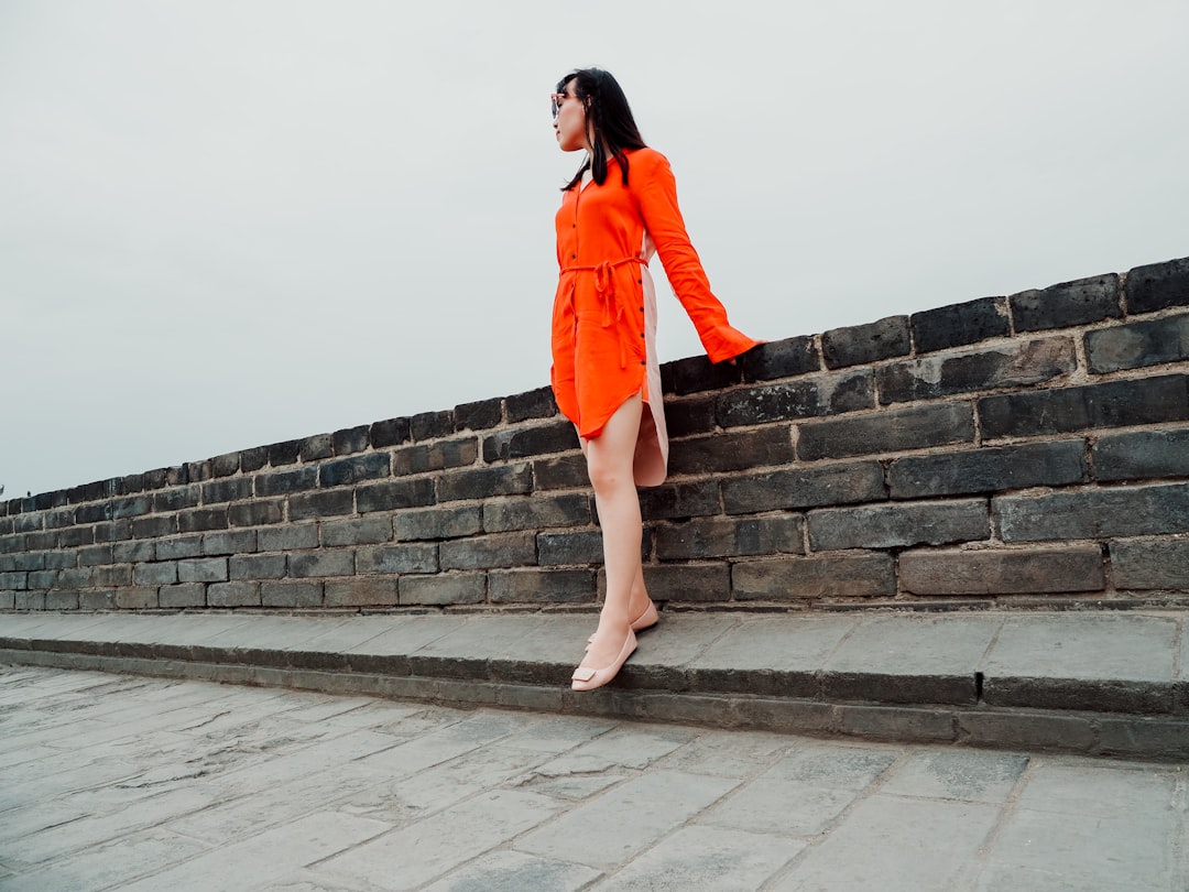 woman standing beside brick wall