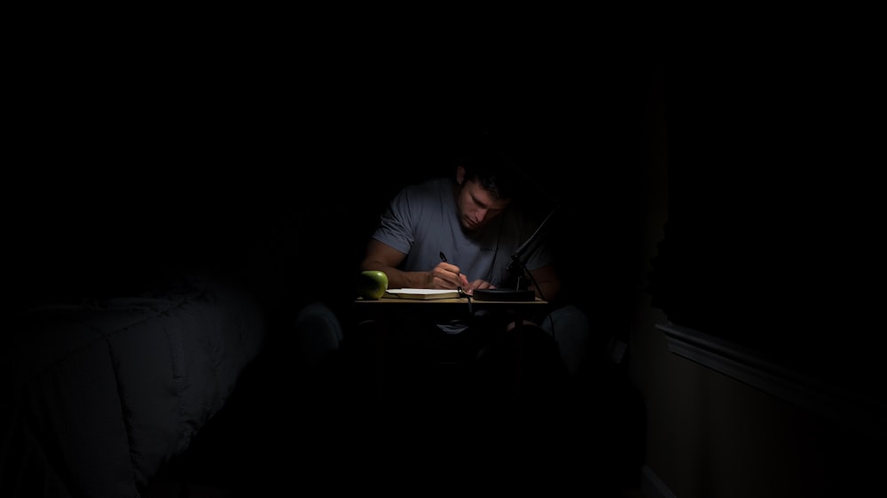 man writing in dark room