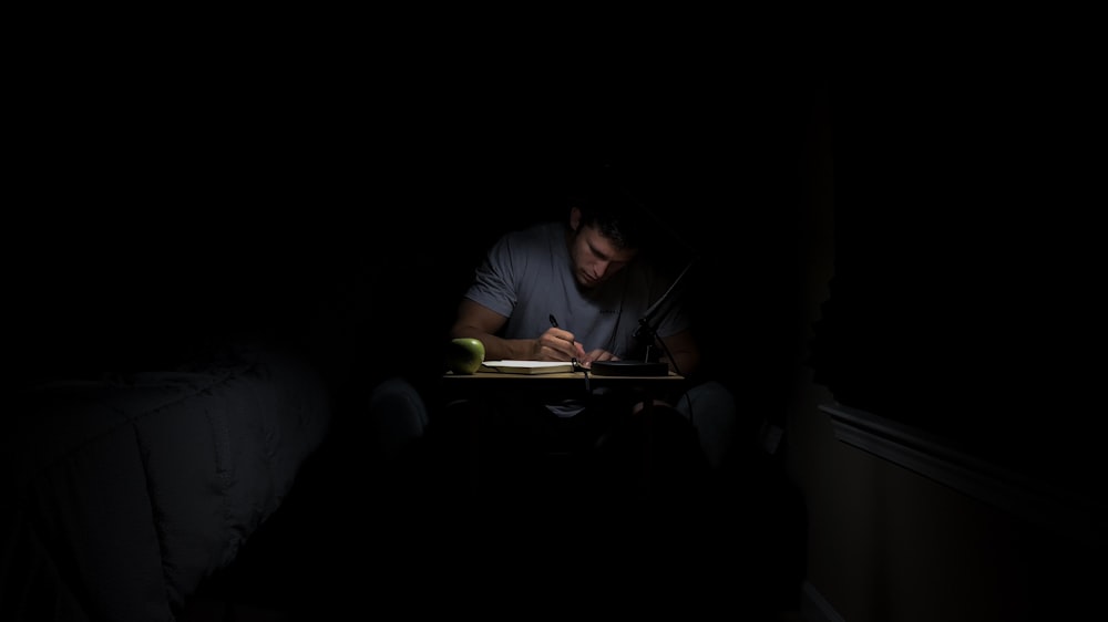 hombre escribiendo en cuarto oscuro