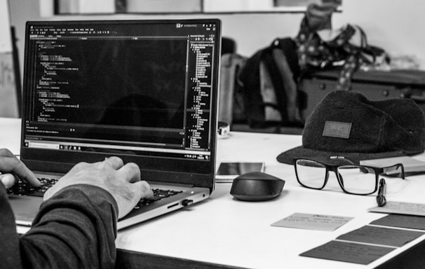 grayscale photo of man using laptop coding