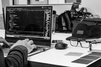 grayscale photo of man using laptop coding