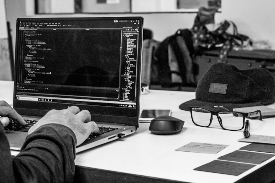 grayscale photo of man using laptop coding