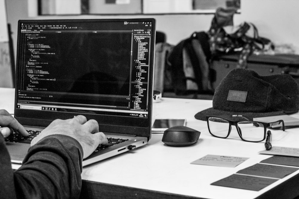 grayscale photo of man using laptop coding