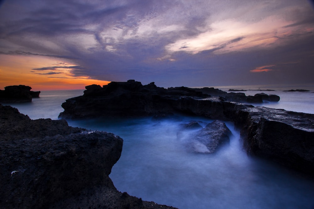 gray rock formation on body of water