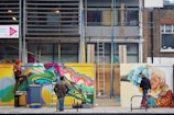 Young creatives collaborating on murals outdoors blending paint and spray cans.